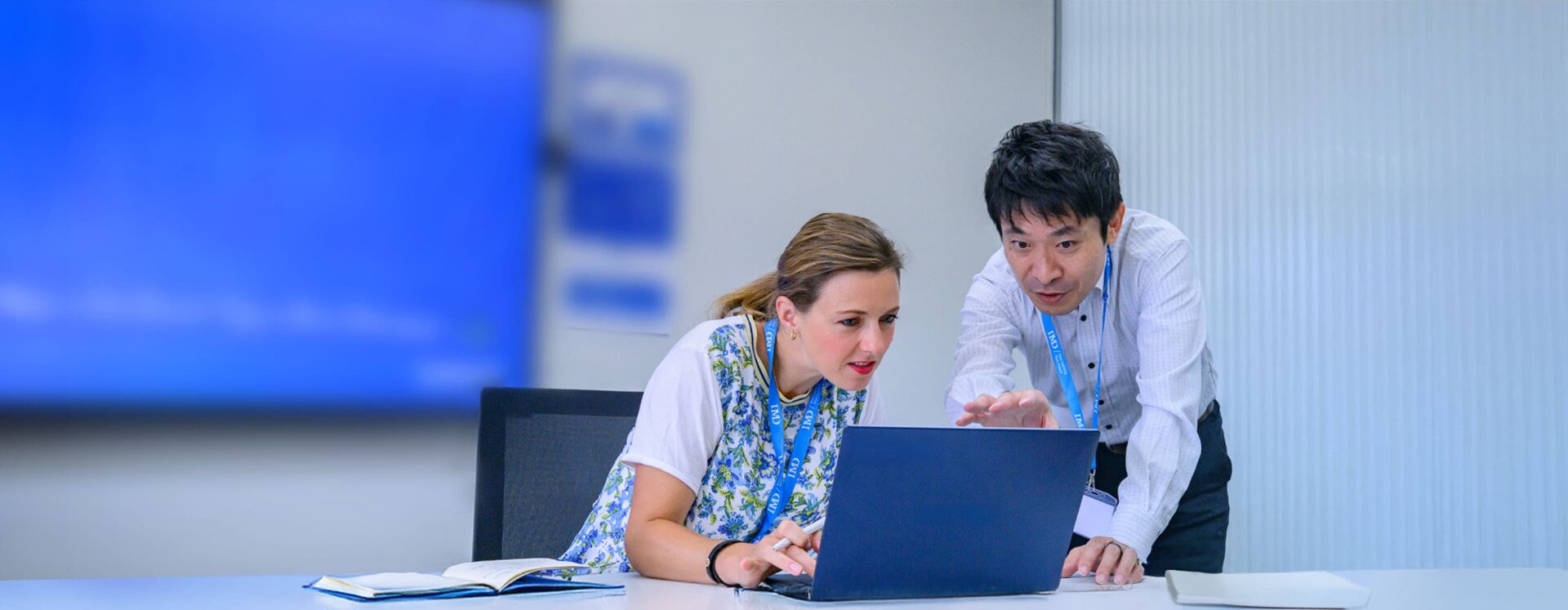 Executive learning AI and digital business transformation - IMD Business School Professional executives engages in a strategy session with digital tools, representing AI and digital business transformation. - IMD Business School
