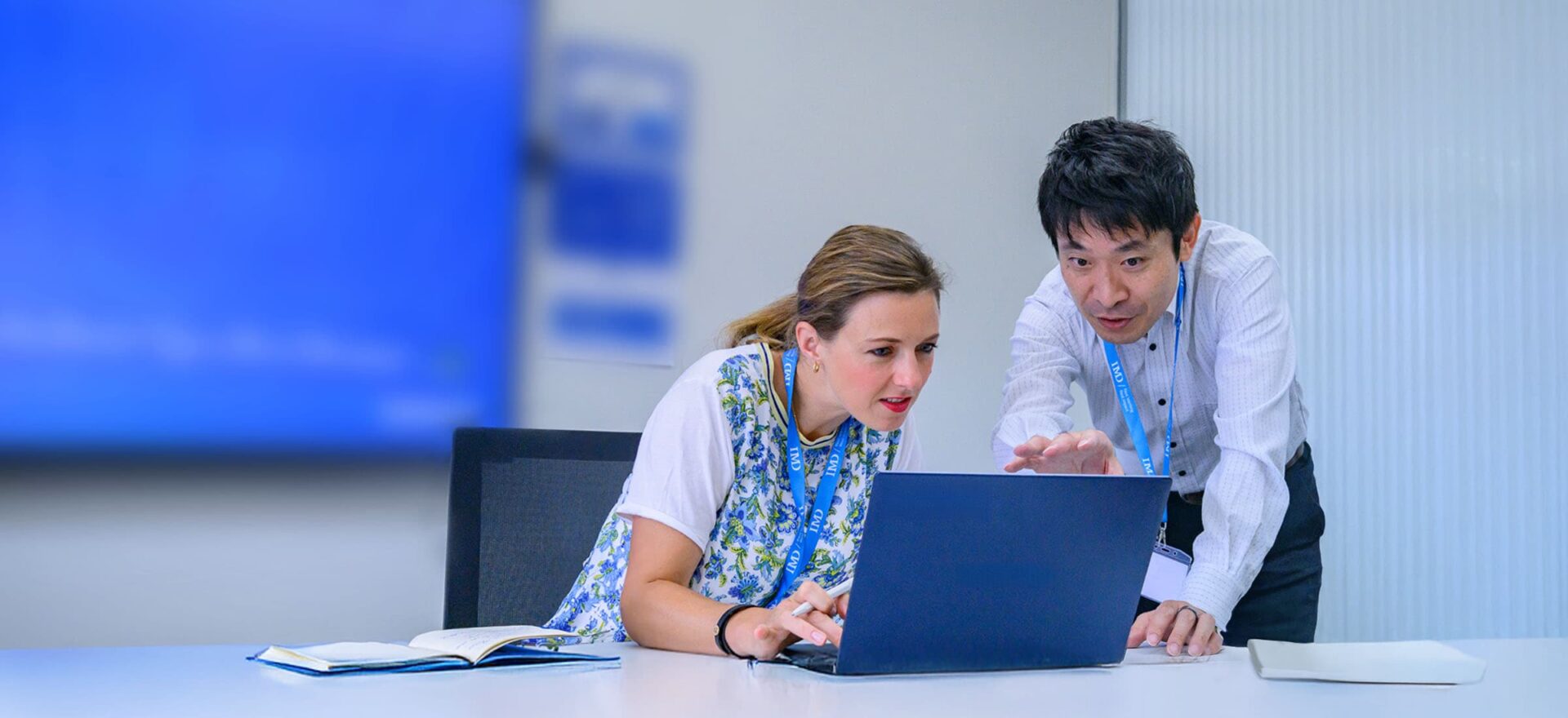 Executive learning AI and digital business transformation_medium - IMD Business School Professional executives engage in a strategy session with digital tools, representing AI and digital business transformation. - IMD Business School